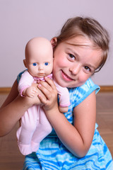 Little girl playing with her baby doll and pretending mom