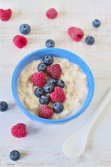 Oatmeal porridge with blueberries and raspberries in bowl - healthy rustic breakfast for kids