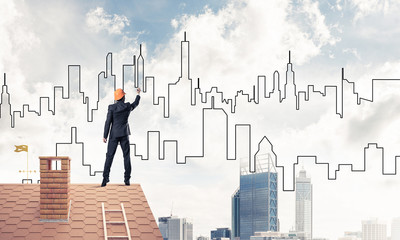 Man architect draw silhouette of modern city on blue sky. Mixed 