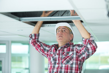 repairman fixing cables in the ceiling
