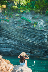 Young girl in a cove on a rock in the Cinque Terre Reserve. Stunning nature and fresh air