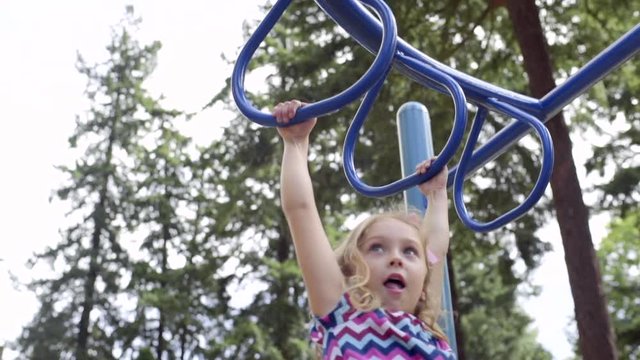 Strong Little Girl Plays On Monkey Bars At Playground (Slow Motion)