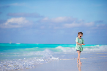 Fototapeta na wymiar Adorable little girl walking along white sand caribbean beach