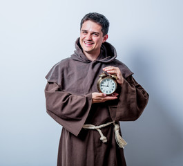 Portrait of Young catholic monk with alarm clock