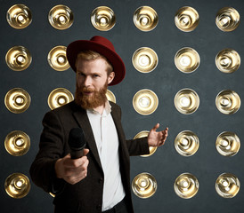 Attractive charming young European singer wearing stylish elegant clothing holding mic in his...