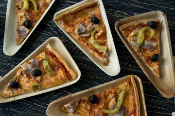 A slices of pizza is on a wooden plate.