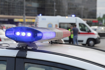 Blue light flasher atop of a police car. City lights on the background.