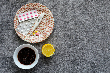 Thermometer, jam, lemon, tablets for colds on the grey background