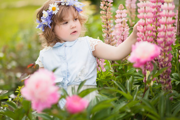 happy toddler girl with a flower wreath in the garden