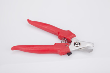A pair of red dog nail clipper on a white surface. Pet nail clipper isolated on white background.