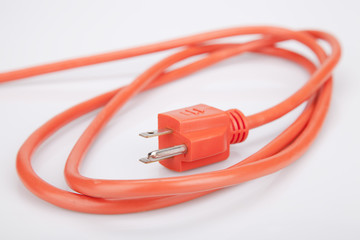 Bright orange extension cord on a white surface. Orange extension cable isolated on white...