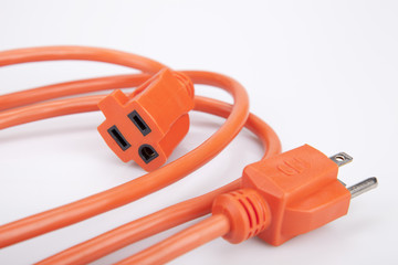 Bright orange extension cord on a white surface. Orange extension cable isolated on white background.