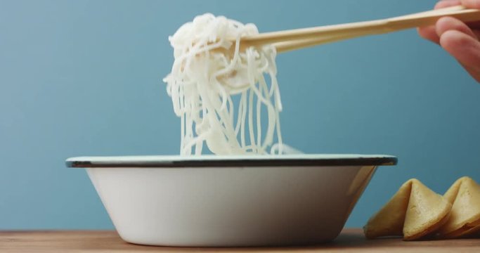 man's hand with a asian sticks take a part of rice noodles
