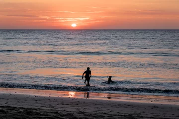 Poster Man and dog silhouette at Beautiful sunset in Mancora Beach - Mancora, Peru © diegograndi