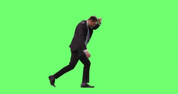 Businessman in a Suit Walking Against Strong Wind Trying to Cover His Face with Arm. Shot on Mock-up Green Screen.