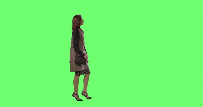Casual Brunette Female is Walking on a Mock-up Green Screen in the Background.