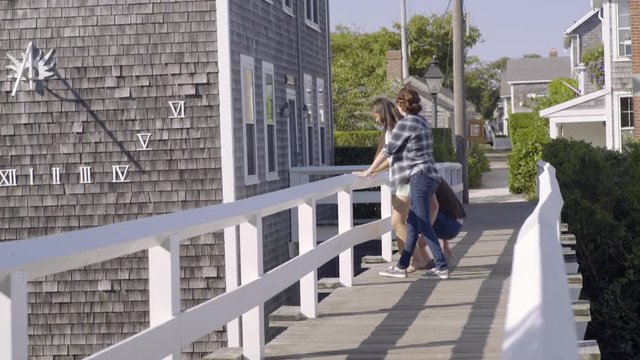 Multiethnic Teens Hang Out On Bridge, They Get Up, Guy Gives Girl Piggyback Ride, And They All Run Toward Camera