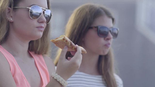Teen Girls Eat Pizza, One Checks Her Phone, They Laugh 