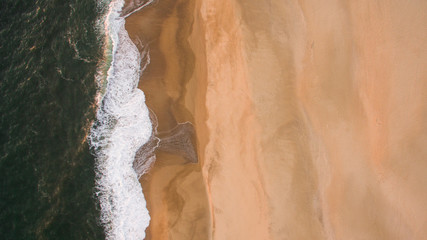 Aerial view of ocean sea waves on sandy beach at evening