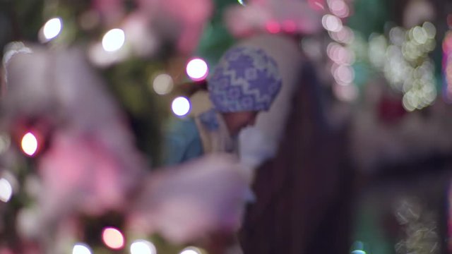 Little Girl Peaks Out From Behind Snow Covered Christmas Tree, She Leans Over Bridge To Look At Pond (Slow Motion)