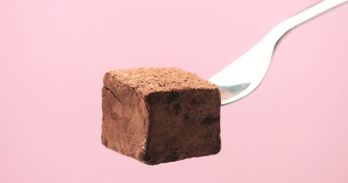 truffle cube on a fork and cacao powder falling on it
