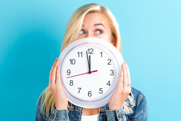 Young woman holding a clock showing nearly 12