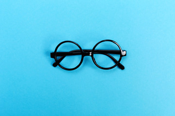 A pair of round glasses on a bright blue background