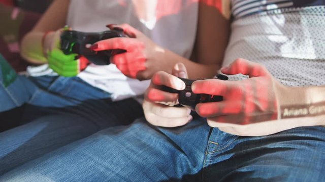 Close up shot of couple hands who playing video game while sitting on sofa.