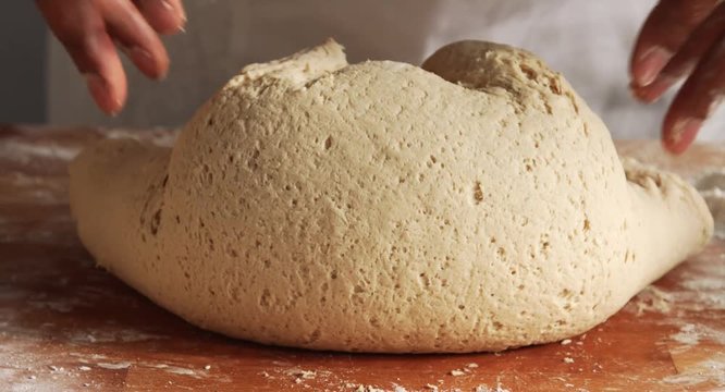 mixed race man's hand kneading a dough on wood and make a ball from it
