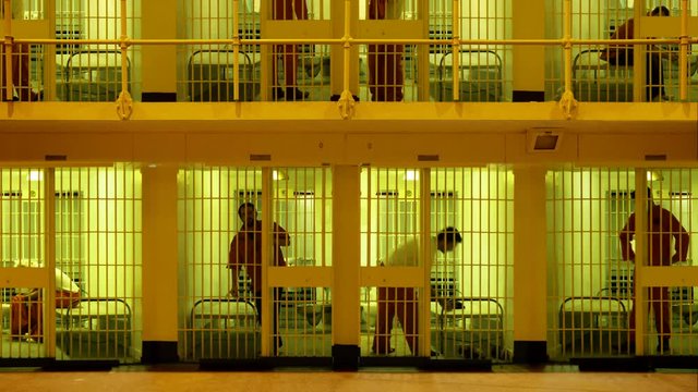 Prisoners serving time in a large cell block.  Composite clip created by putting together six videos together with masking in After Effects. 4K UHD version.