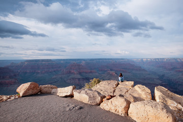 Person sitting on rock looking into the scenic Grand Canyon