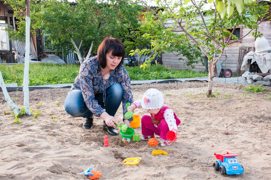 Brunette Mom Playing With Her Baby In The Sandbox