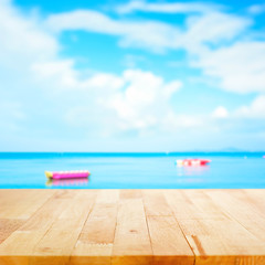 Fototapeta na wymiar Wood table top on blur summer sky and sea with banana boats as background