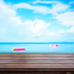 Wood table top on blur summer sky and sea with banana boats as background