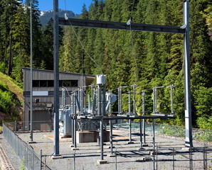 Fototapeta na wymiar Electrical Substation on mountain river on the background of green trees and blue sky.