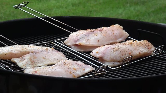 Man's hands cooking fish fillet on grill
