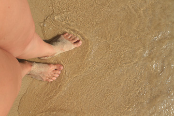 Female feet in the sand. on top of female feet on a sandy beach with footprints