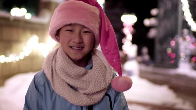 Little Girl Dressed In Santa Hat Smiles For Portrait In Winter Wonderland (Slow Motion)