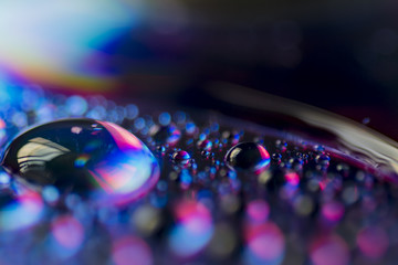 Fototapeta na wymiar Compact Disc CD with water drops on the data surface with a shiny colorful reflection