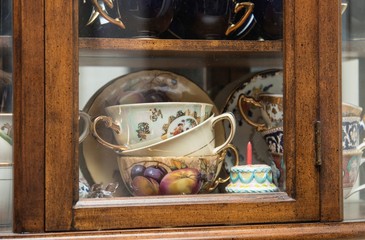Vintage curio cabinet with porcelain tea cup collection