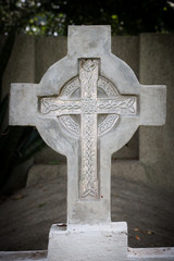 A carved marble cross in an abandoned cemetery