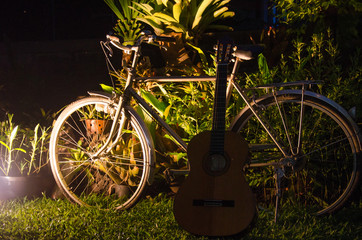 Obraz na płótnie Canvas Old Ancient Bike Park in the lawn and have a leaning guitar. Beautiful night atmosphere