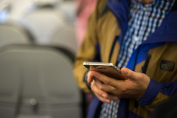 Smart phone on man hand on airplane. Soft focus