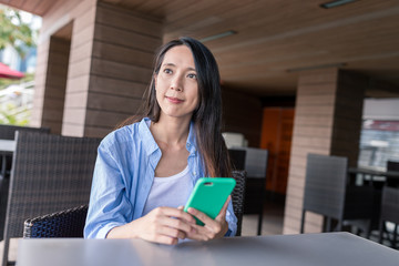Fototapeta premium Woman holding cellphone and looking far away