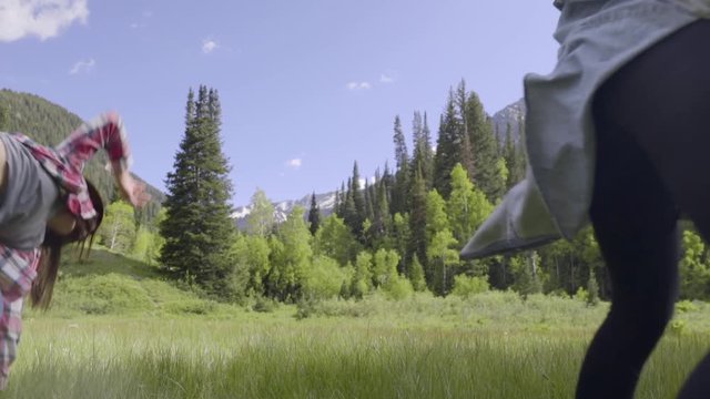 Two Teenage Girls Cartwheel Past Camera In Mountain Meadow (Slow Motion)