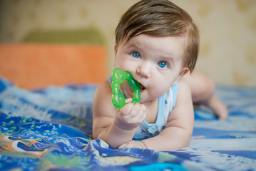 Baby on the bed. Baby and toy. Little girl with toys rattles. Kid with toy. Teethers for babies. Funny toddler. Portrait of a baby. Pretty girl 5 months lying on the bed. plump little girl
