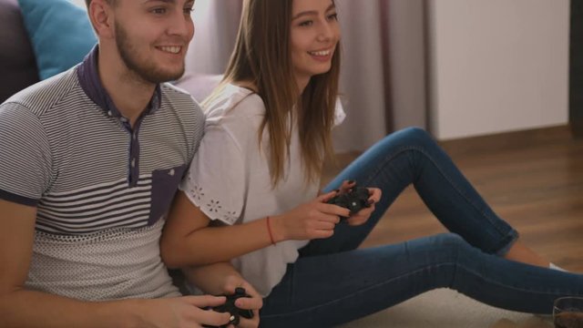 Portrait of emotional young couple eating pizza and playing video game at home.