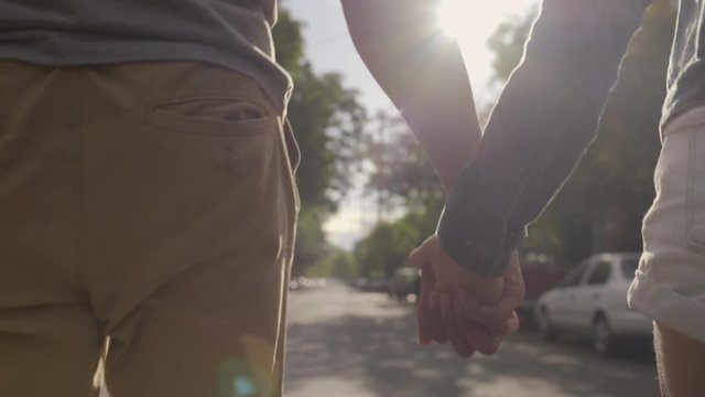 Closeup Of Couple Holding Hands And Walking Down The Middle Of A Neighborhood Street (Slow Motion)