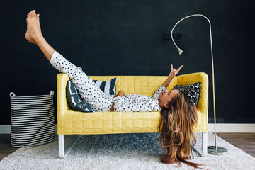 Pre teen child on the couch against black wall in modern living room interior