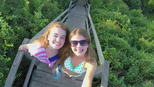 Teen Girls Stand At Top Of Stairs On Beach, They Take Birds Eye View Gopro Footage Of Themselves Smiling